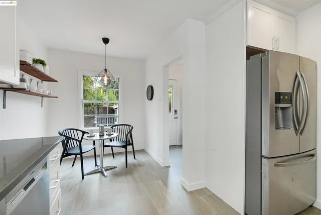 a kitchen with stainless steel appliances granite countertop a refrigerator a microwave a dining table and chairs with wooden floor