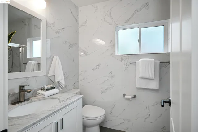 a bathroom with a granite countertop toilet sink and mirror