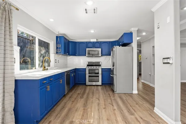 a kitchen with stainless steel appliances granite countertop a refrigerator a sink dishwasher and a stove with wooden floor