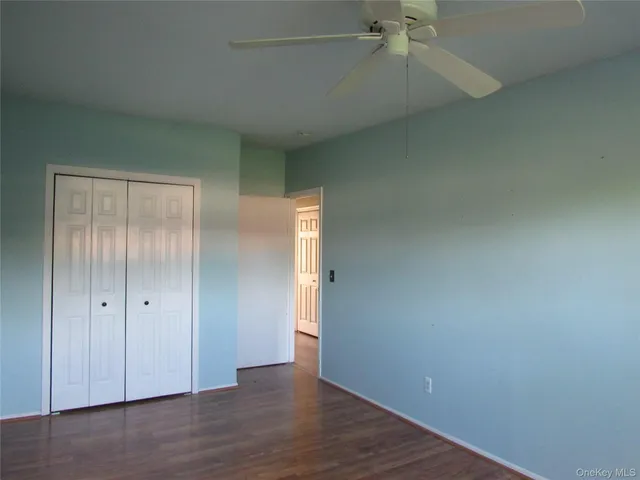 an empty room with wooden floor closet and windows