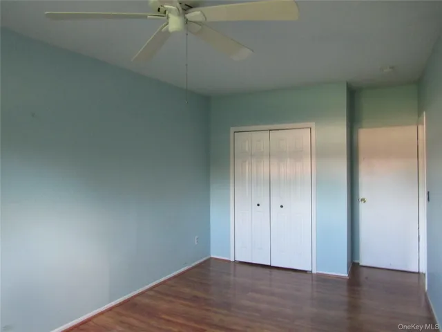 an empty room with wooden floor closet and windows