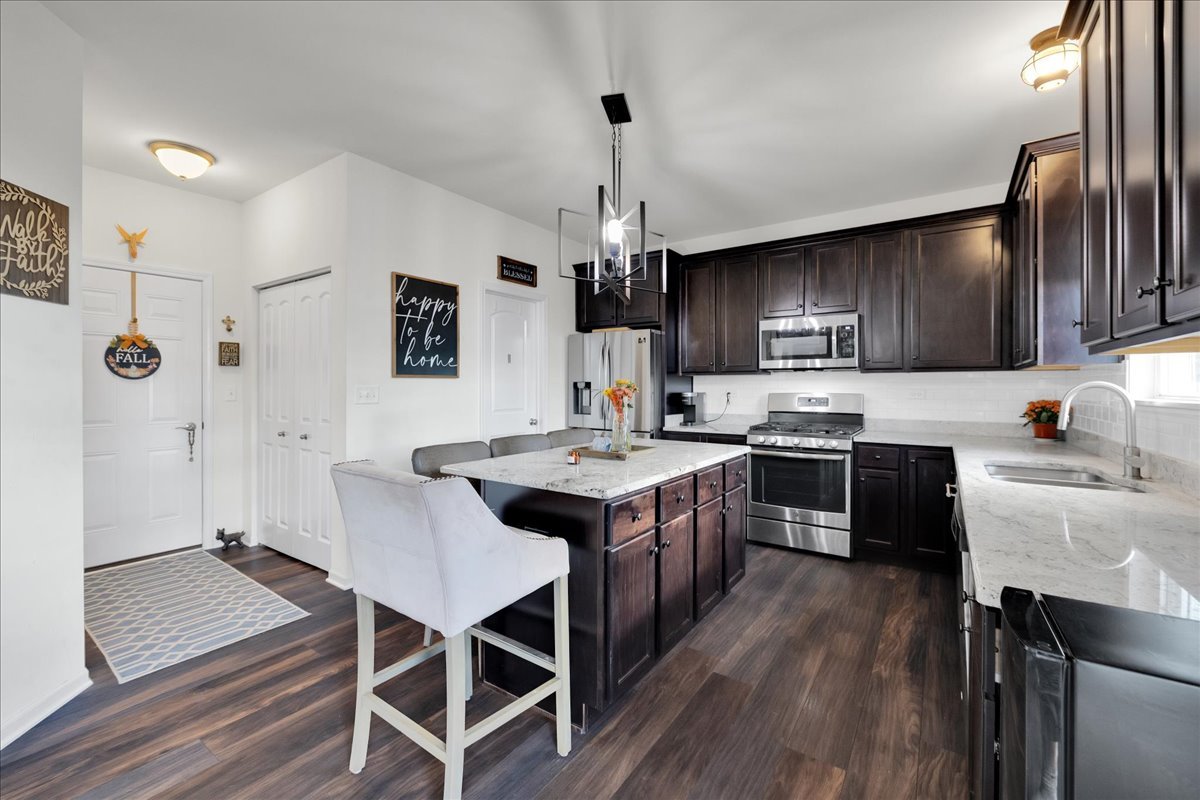 435 Fawn Lane Oswego, IL 60543 - Photo 11 of 47 a kitchen with kitchen island granite countertop wooden floors and stainless steel appliances