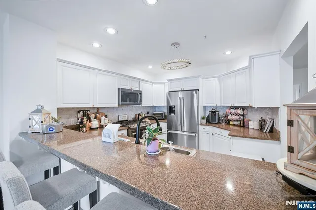 a kitchen with stainless steel appliances granite countertop a sink refrigerator and cabinets