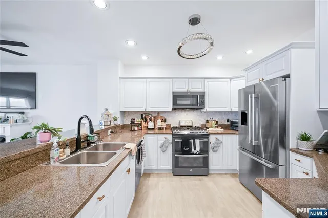 a kitchen with stainless steel appliances granite countertop a sink stove refrigerator and microwave