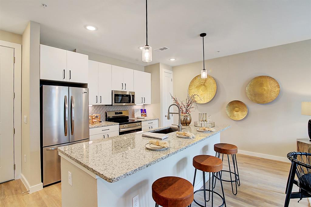 a kitchen with stainless steel appliances granite countertop a stove a kitchen island a dining table and chairs
