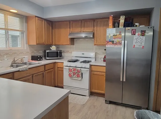 a kitchen with stainless steel appliances a refrigerator a sink a stove and white cabinets