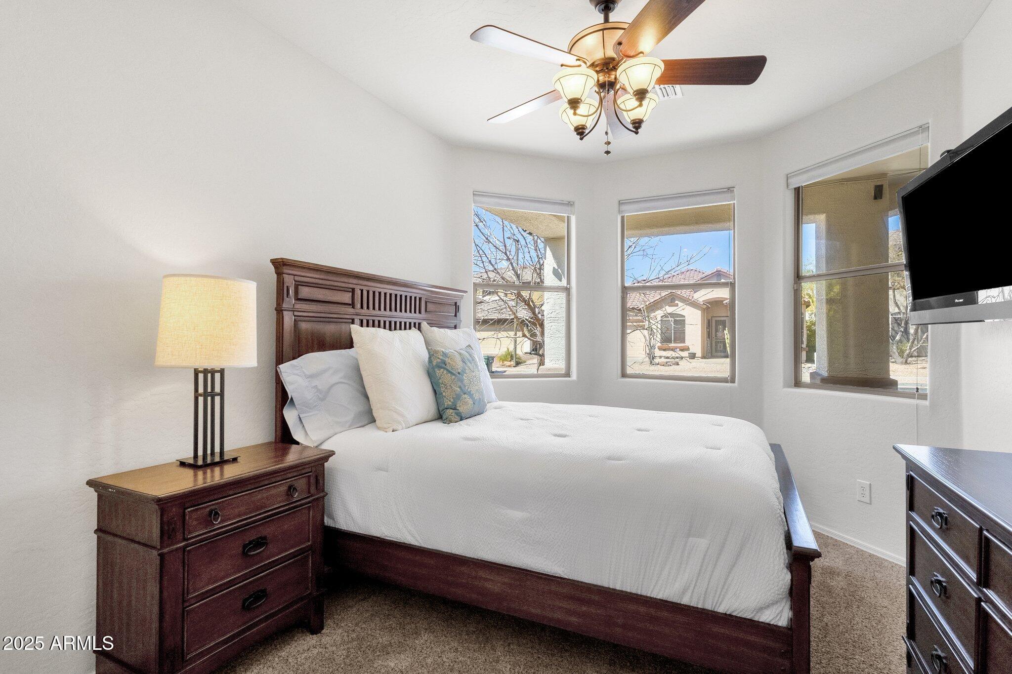 2417 West Apache Rain Road Phoenix, AZ 85085 - Photo 5 of 41 a bedroom with a bed a flat screen tv and a chandelier
