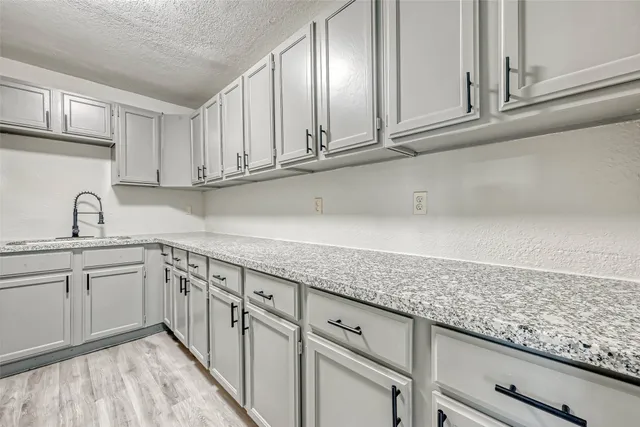 a kitchen with granite countertop white cabinets and sink