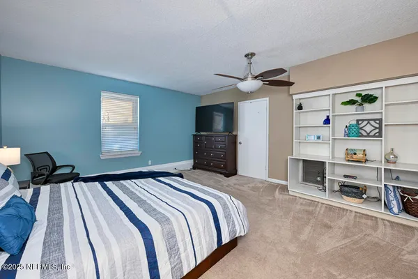 a bedroom with a bed and a flat tv screen on dresser
