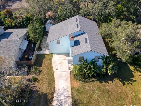 an aerial view of a house with a yard and large tree