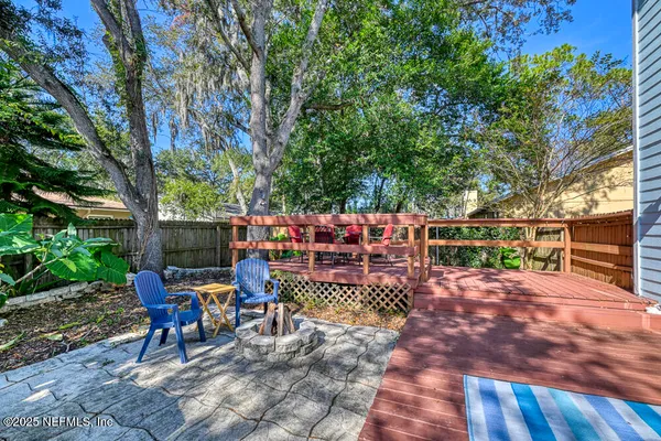 a view of a patio with table and chairs potted plants and large tree