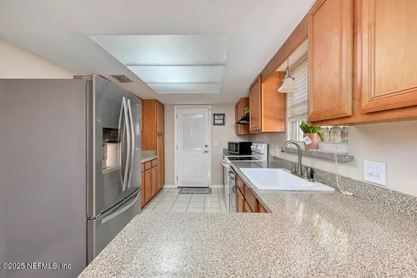 a kitchen with stainless steel appliances granite countertop a refrigerator a sink and white cabinets