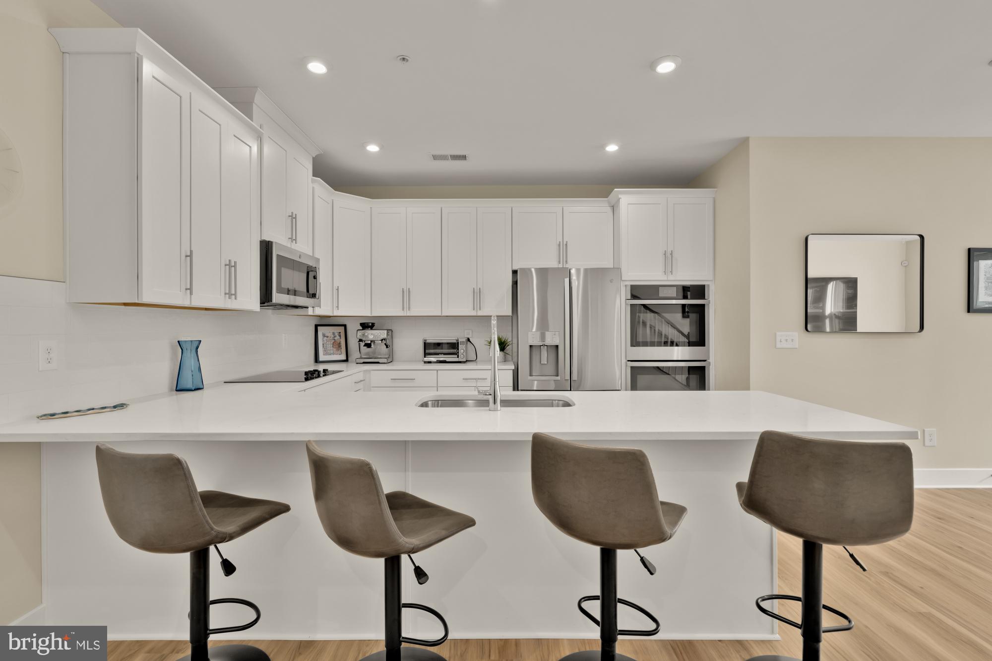 1704 Bandit Loop, Unit 20A Reston, VA 20190 - Photo 7 of 32 a kitchen with stainless steel appliances granite countertop a sink a stove a refrigerator and white cabinets with wooden floor