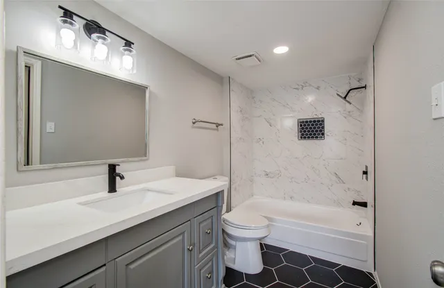 a bathroom with a sink a toilet and shower