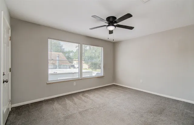 an empty room with windows and fan