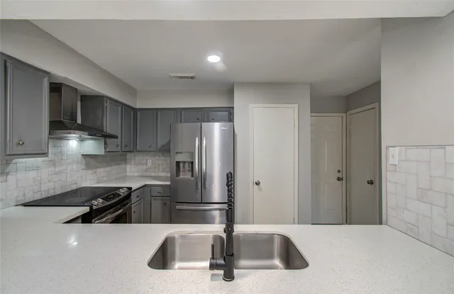 a kitchen with stainless steel appliances a sink a refrigerator and cabinets