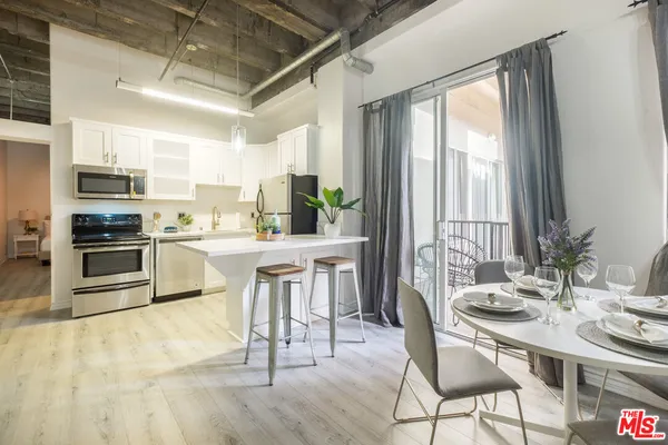 a kitchen with kitchen island a dining table chairs stainless steel appliances and a large window