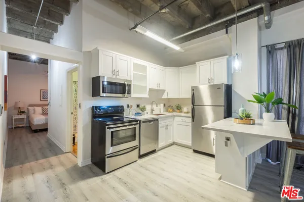 a kitchen with refrigerator a microwave a stove and white cabinets