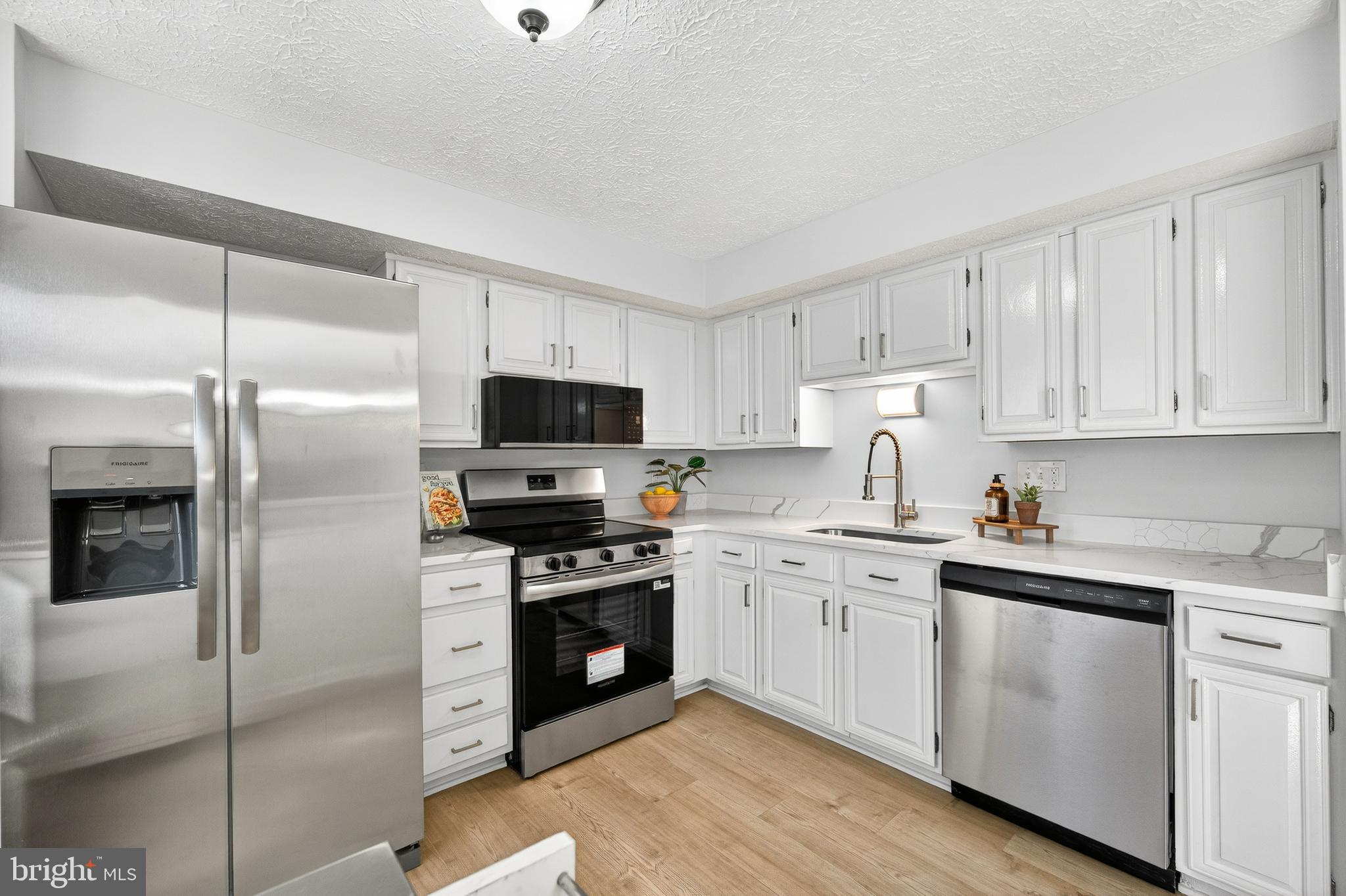 8225 Burning Forest Court Springfield, VA 22153 - Photo 12 of 43 a kitchen with white cabinets stainless steel appliances and a counter space