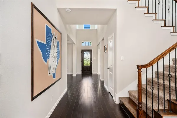 a view of a hallway with wooden floor and stairs