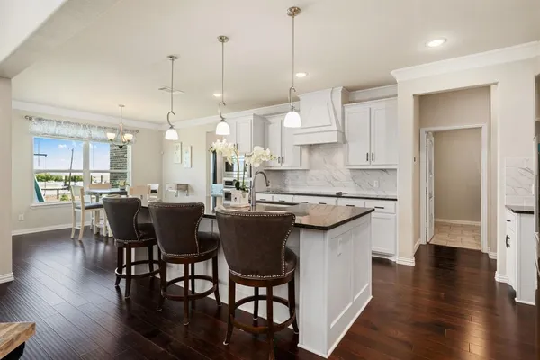 a kitchen with stainless steel appliances granite countertop a stove a sink a refrigerator a dining table and chairs with wooden floor