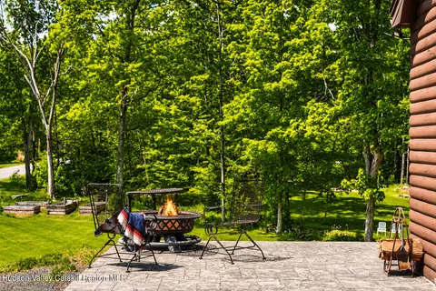 a backyard of a house with table and chairs under an umbrella