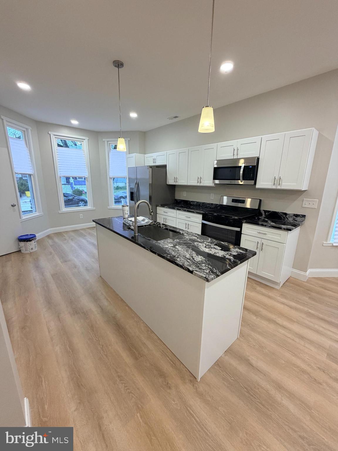 3 East Overlea Avenue, Unit 3 Baltimore, MD 21206 - Photo 23 of 45 a large kitchen with stainless steel appliances granite countertop a stove a sink a refrigerator a microwave oven with white cabinets and wooden floor