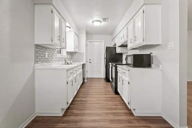 a kitchen with stainless steel appliances a white cabinets and wooden floor