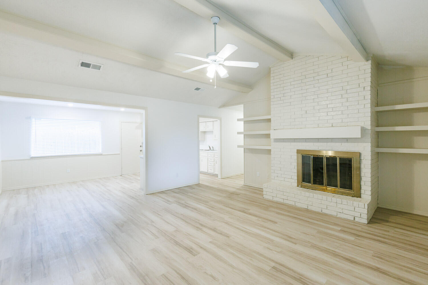4407 75th Drive, Unit B Lubbock, TX 79424 - Photo 3 of 20 an empty room with wooden floor a fireplace a ceiling fan and windows