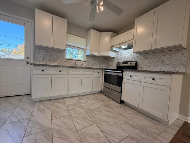 a kitchen with granite countertop white cabinets stainless steel appliances and a counter space
