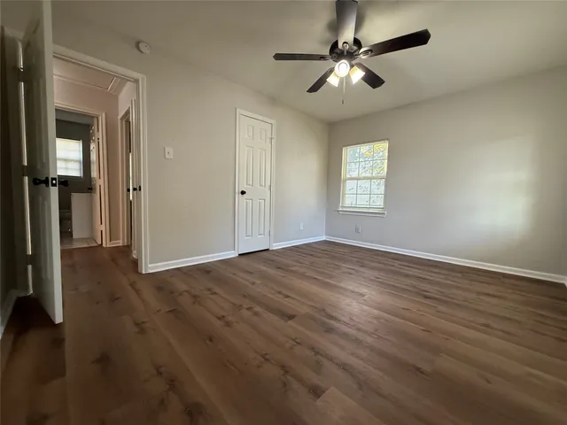 a view of empty room with wooden floor and fan