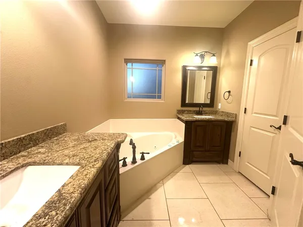 a spacious bathroom with a granite countertop sink and a bathtub