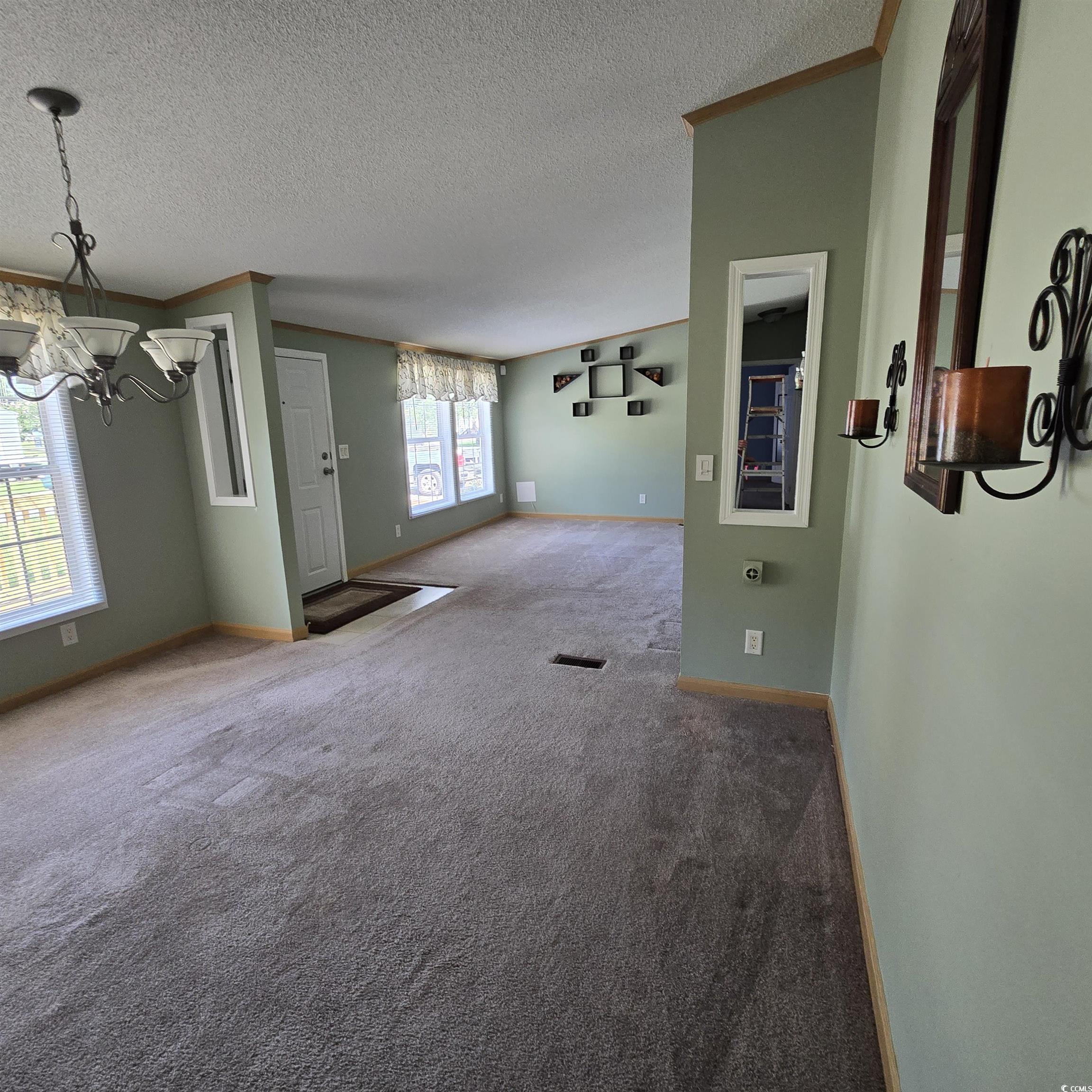 34 Talon Circle Murrells Inlet, SC 29576 - Photo 11 of 40 Unfurnished living room with a chandelier, crown molding, carpet, and a textured ceiling