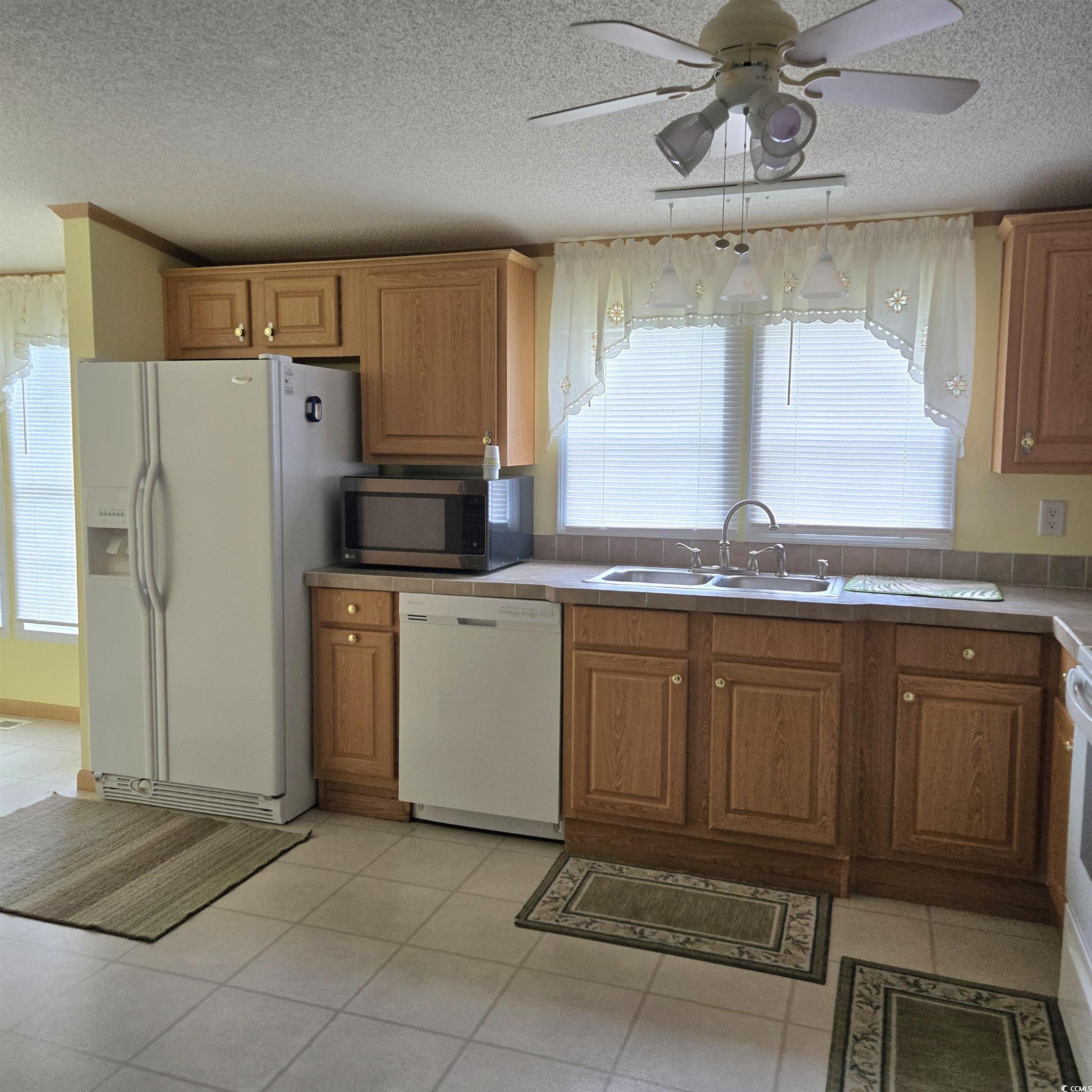 34 Talon Circle Murrells Inlet, SC 29576 - Photo 15 of 40 Kitchen with a textured ceiling, white appliances, a ceiling fan, light tile patterned floors, and brown cabinets