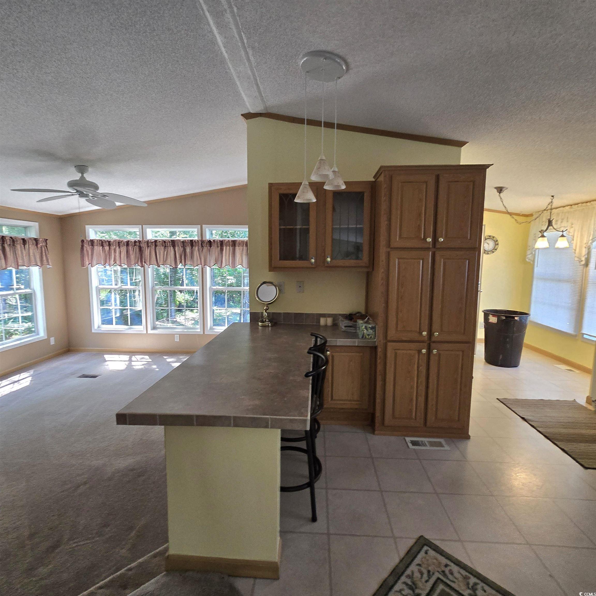 34 Talon Circle Murrells Inlet, SC 29576 - Photo 18 of 40 Kitchen with a peninsula, lofted ceiling, healthy amount of natural light, a textured ceiling, and brown cabinets