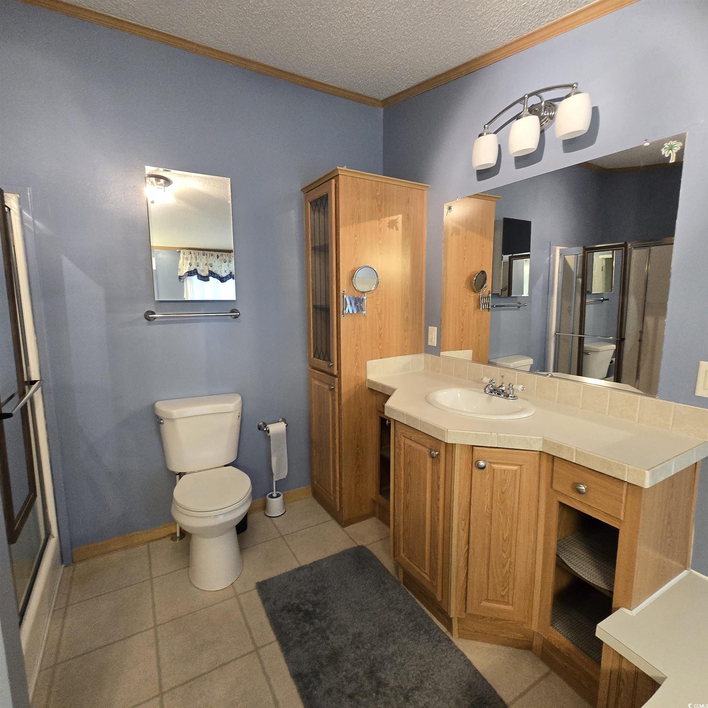 34 Talon Circle Murrells Inlet, SC 29576 - Photo 25 of 40 Full bathroom featuring ornamental molding, tile patterned flooring, a textured ceiling, vanity, and a shower stall