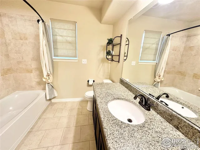 a bathroom with a granite countertop sink a mirror a bathtub and shower