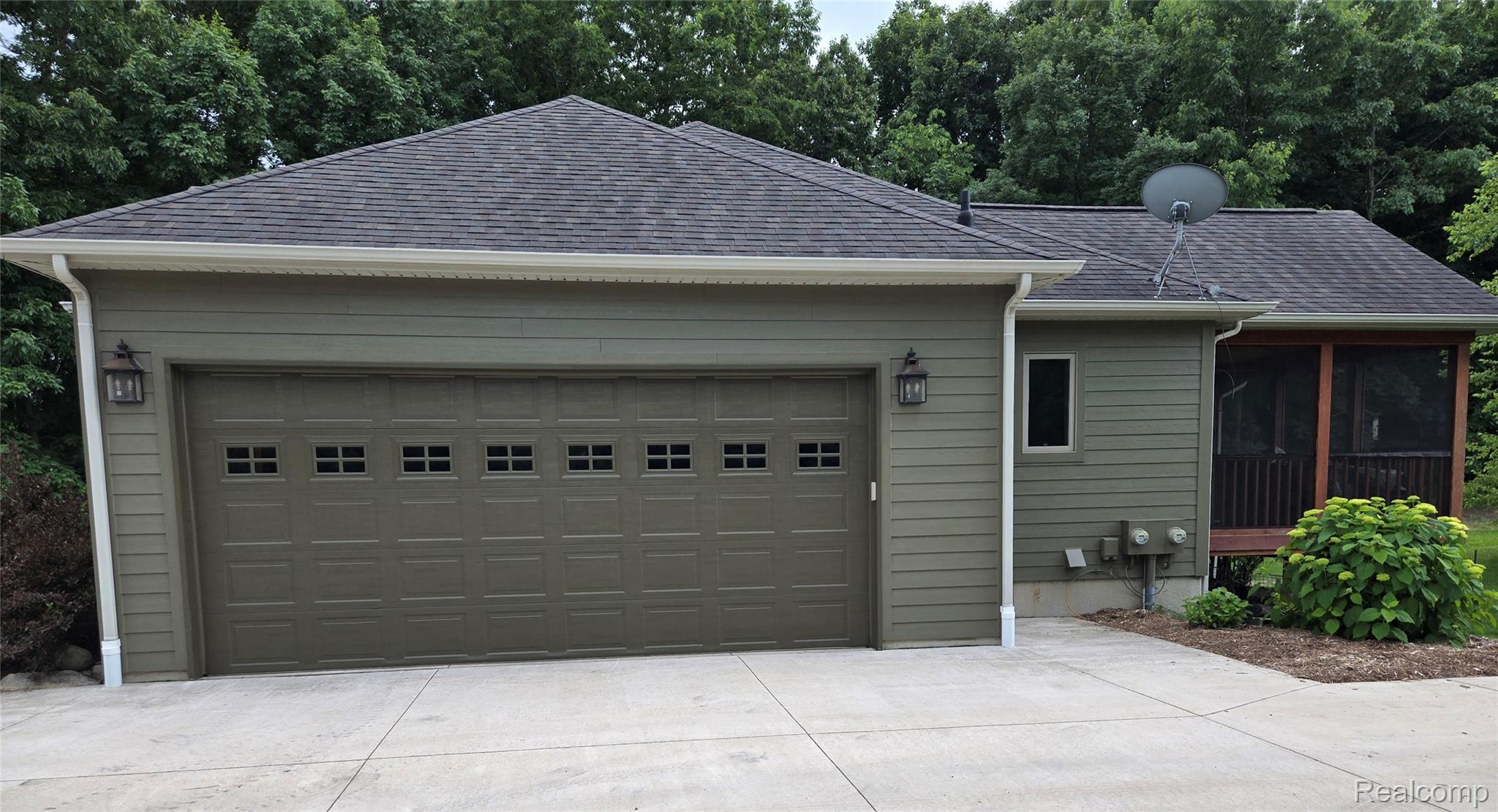 9887 Hadley Road Clarkston, MI 48348 - Photo 37 of 59 Two-car garage with panel-style door, exterior lighting, and a screened porch