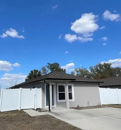 a view of a white house with a big yard and large tree