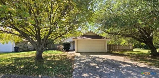 a front view of a house with a yard and large trees