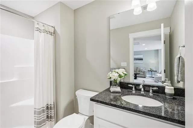 a bathroom with a granite countertop sink a toilet and a mirror
