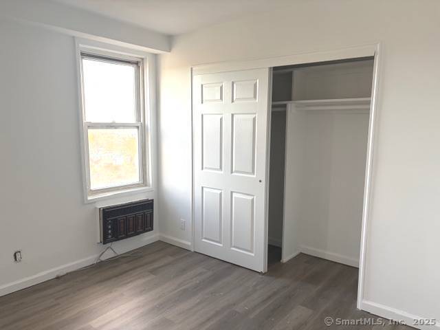 91 Strawberry Hill Avenue, Unit 925 Stamford, CT 06902 - Photo 6 of 20 an empty room with wooden floor cabinet and windows