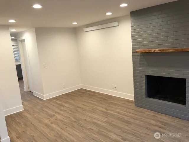 an empty room with wooden floor and a fireplace