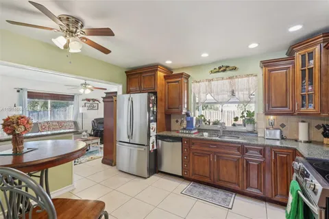 a kitchen with stainless steel appliances granite countertop a refrigerator a stove a sink a dining table and chairs with wooden floor