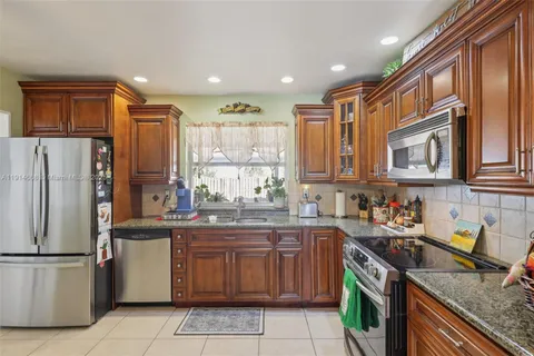 a kitchen with stainless steel appliances granite countertop a sink dishwasher and cabinets with wooden floor