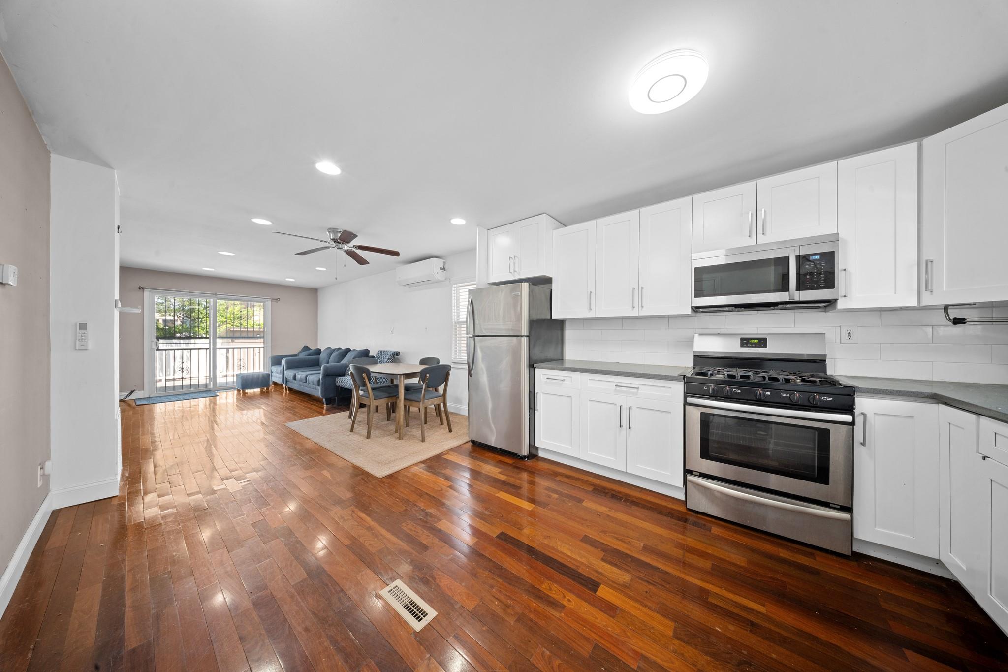 178-15 130th Queens, NY 11434 - Photo 1 of 1 Kitchen with appliances with stainless steel finishes, a wall unit AC, open floor plan, backsplash, and dark wood-style flooring
