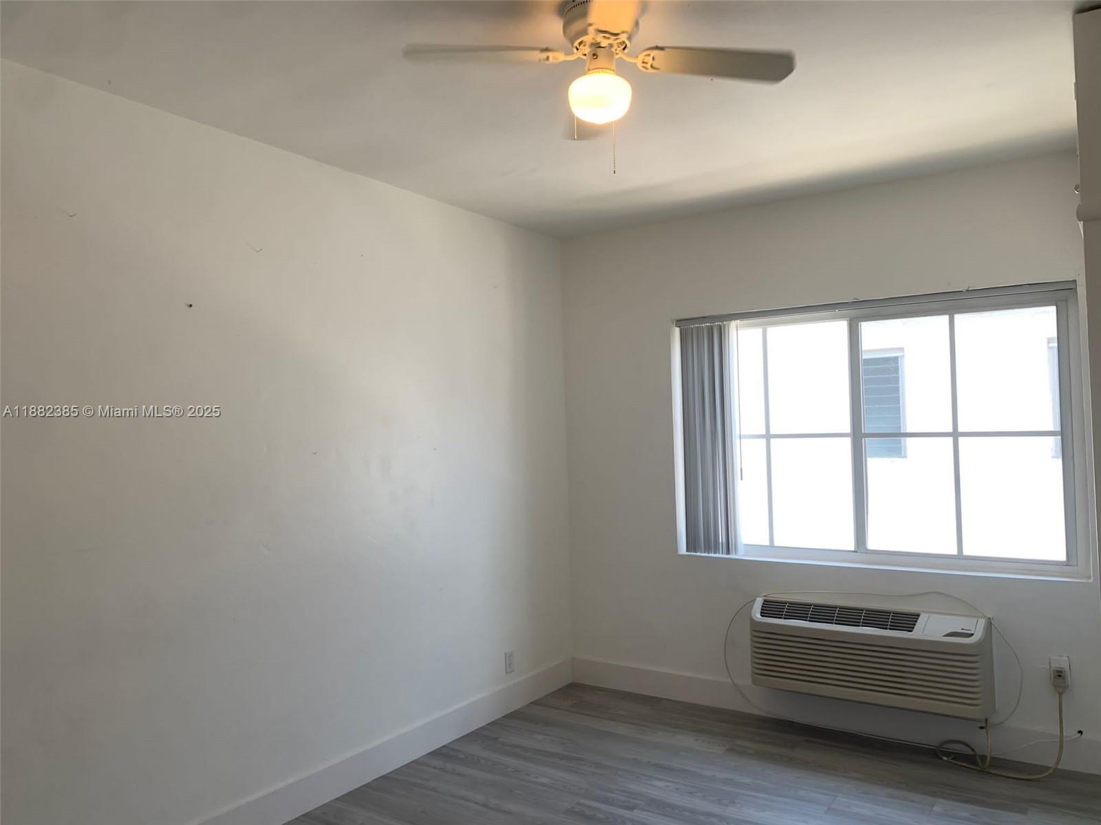 8011 Abbott Avenue, Unit 8 Miami Beach, FL 33141 - Photo 3 of 4 an empty room with wooden floor and windows