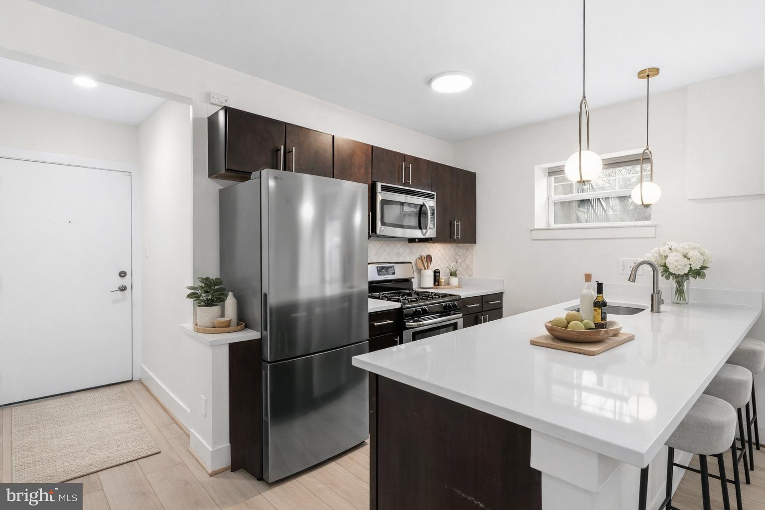 4226 7th Street Northwest, Unit 101 Washington, DC 20011 - Photo 2 of 23 a kitchen with kitchen island a refrigerator stove and microwave