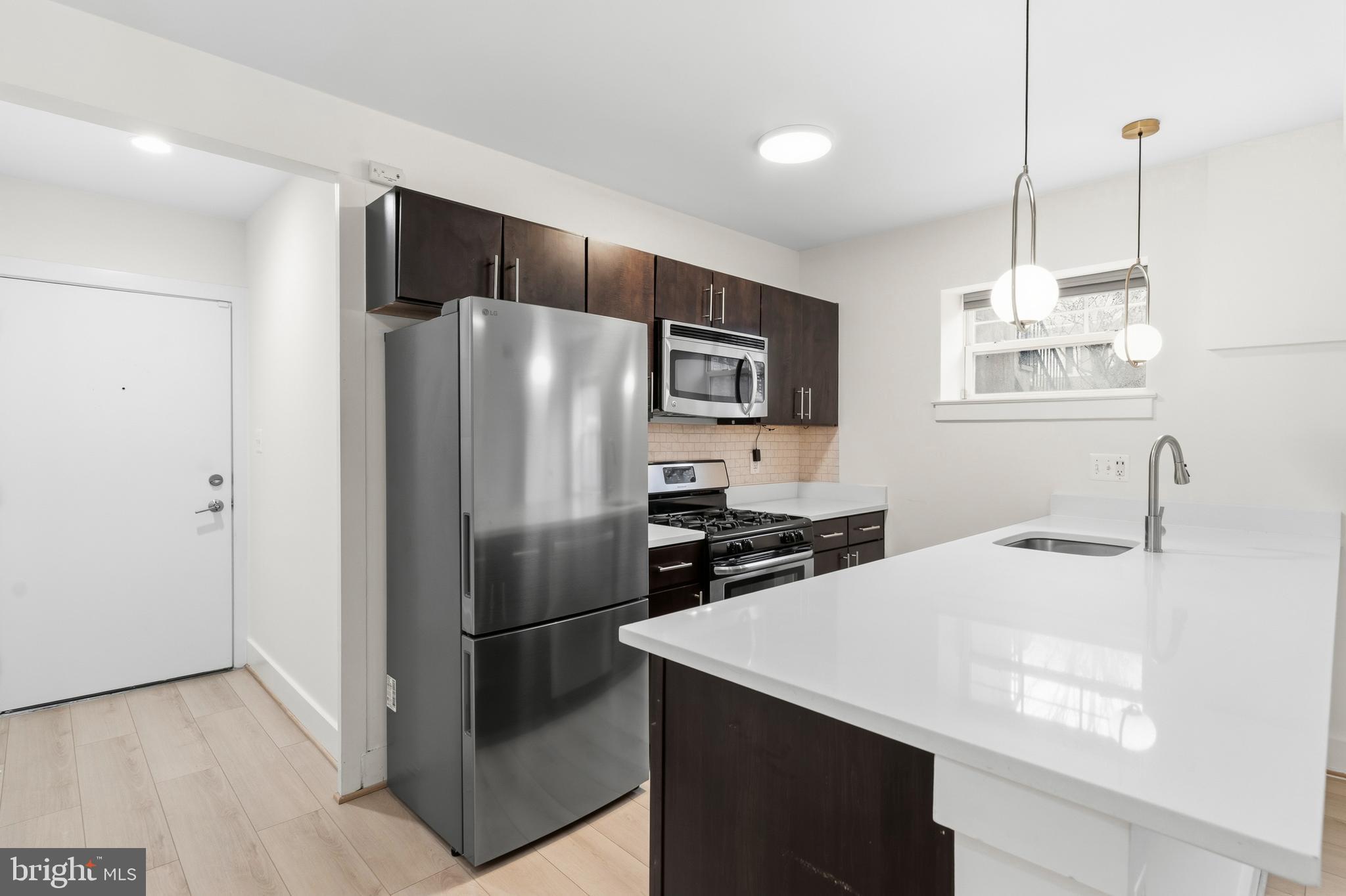 4226 7th Street Northwest, Unit 101 Washington, DC 20011 - Photo 3 of 23 a kitchen with stainless steel appliances a refrigerator sink and microwave
