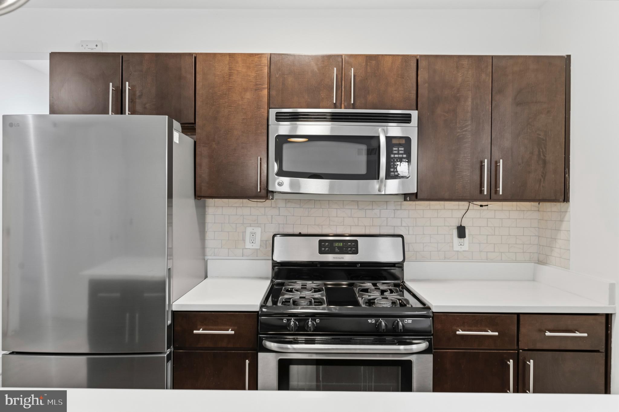 4226 7th Street Northwest, Unit 101 Washington, DC 20011 - Photo 4 of 23 a kitchen with stainless steel appliances wooden cabinets and a stove top oven